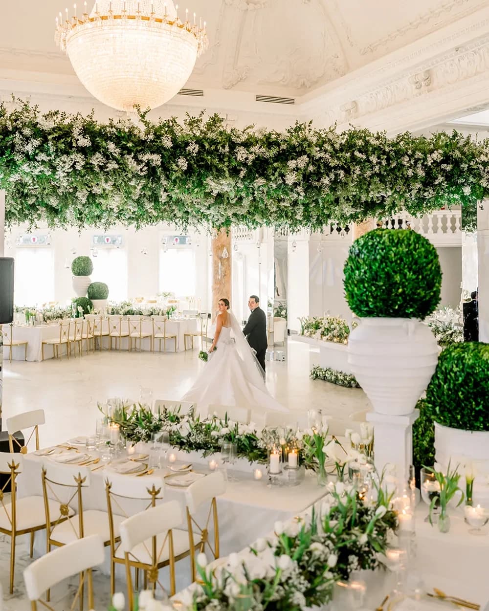 Salón de bodas decorado con arreglos florales colgantes y candelabros